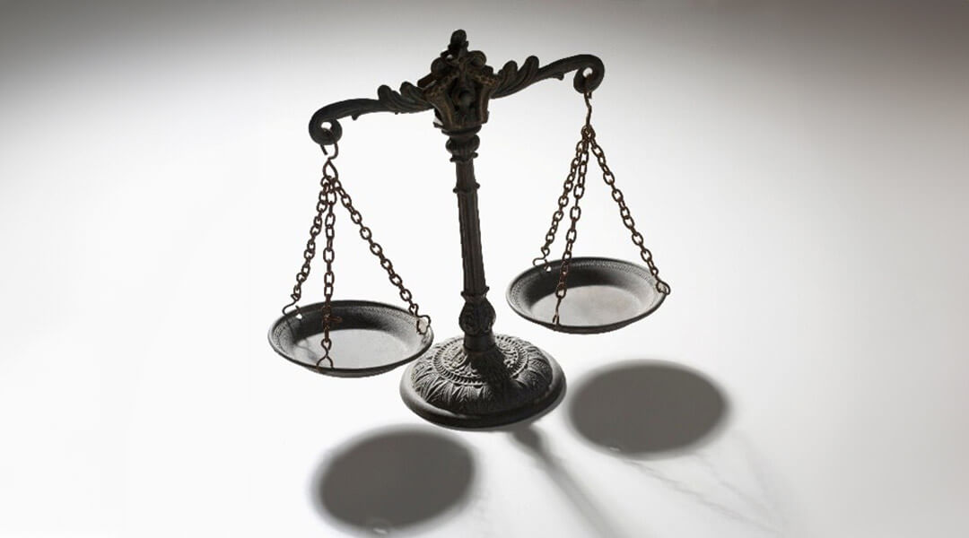 A vintage balance scale casts a shadow on a white surface, symbolizing fairness, equality, and weighing options.